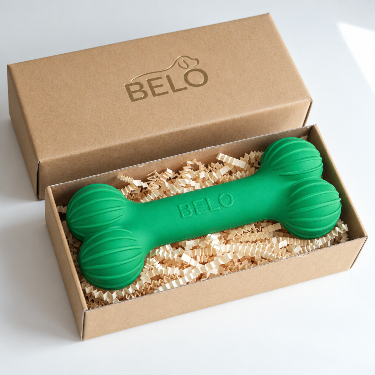 Sprout green BELO Aero Bone dog toy in an open cardboard box beside the branded lid